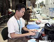 会場バックオフィスにて原稿を書く事務局長